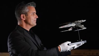 Stephen Lane, Prop Store's chief executive, holds up the light-up X-wing filming miniature from Star Wars: Return of the Jedi, ahead of the auction